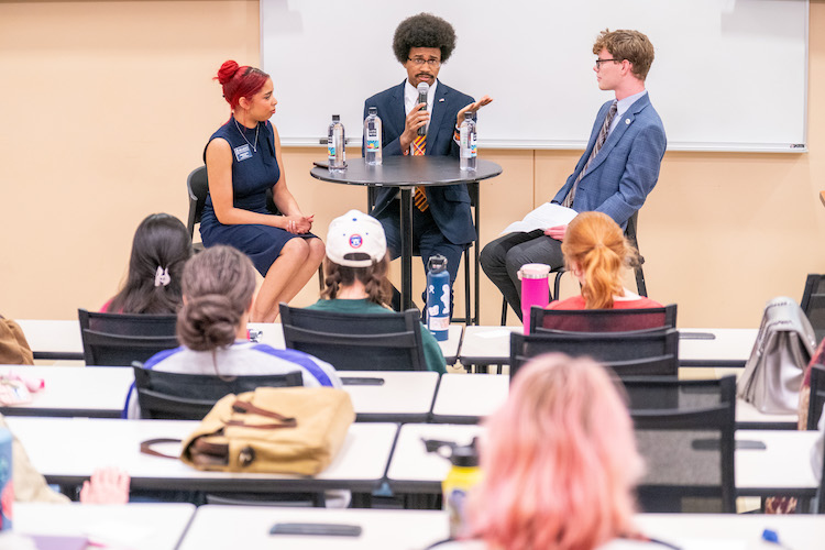 Justin Pearson speaking with two Belmont students in front of classroom full of students