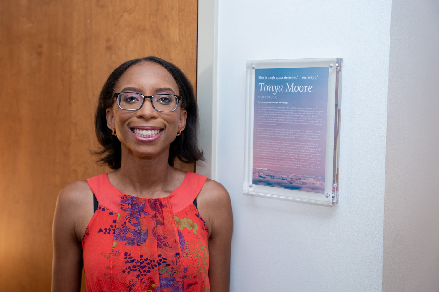 Shardé takes picture with plaque honoring her late mother, Tonya Moore