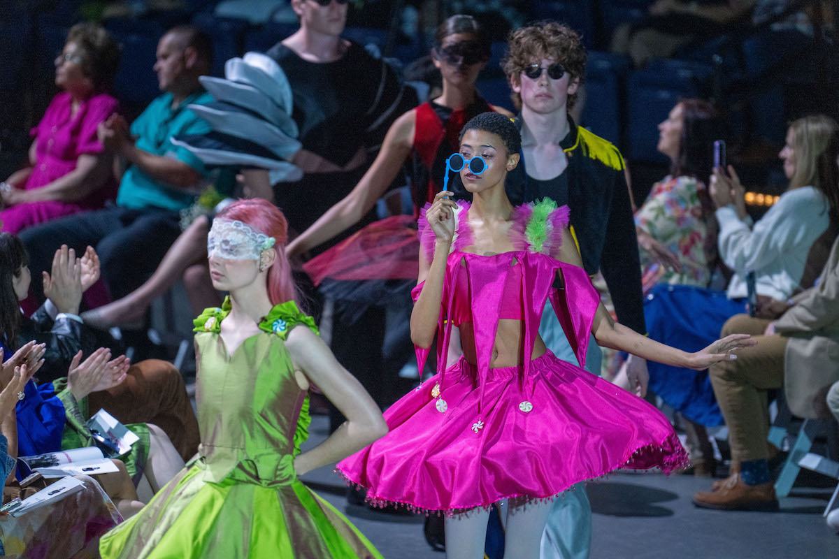 A vibrant, whimsical collection with sculptural silhouettes, including hot pink and neon green dresses.