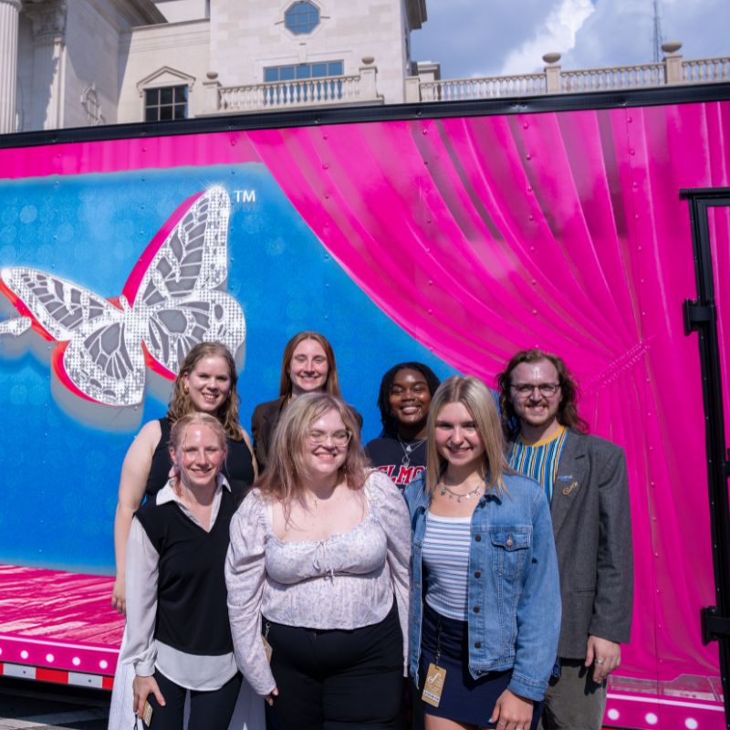 BEST students pose in front of Dolly the Musical signage