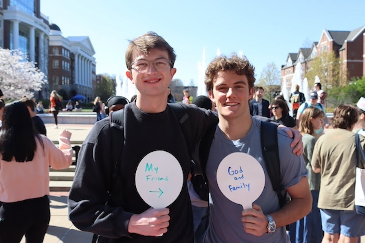 two students with handheld whiteboards sharing what they are grateful for: "my friends" and "God and family"