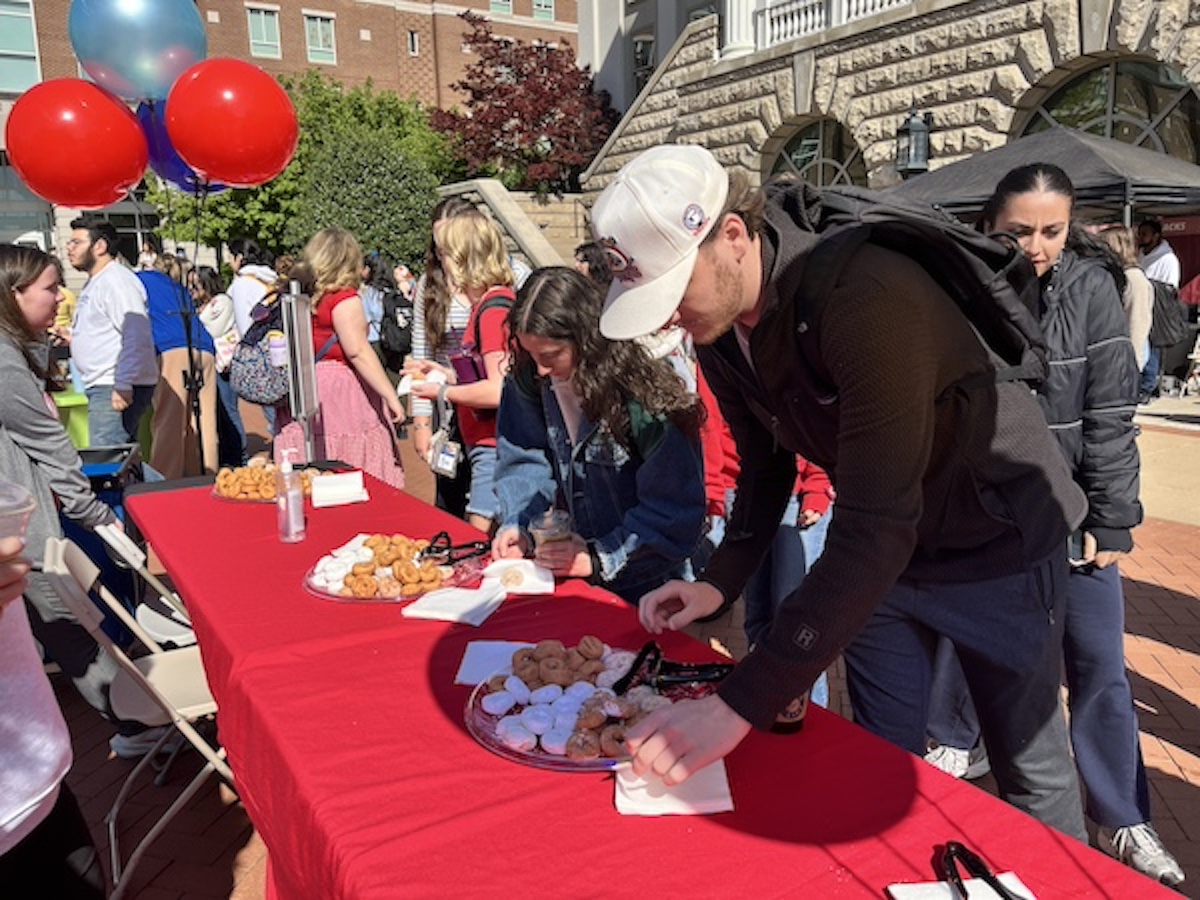 students getting mini donuts off a red table outdoors