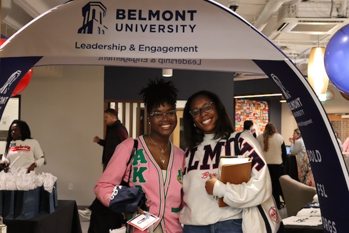 two students smiling and posing under a blue banner