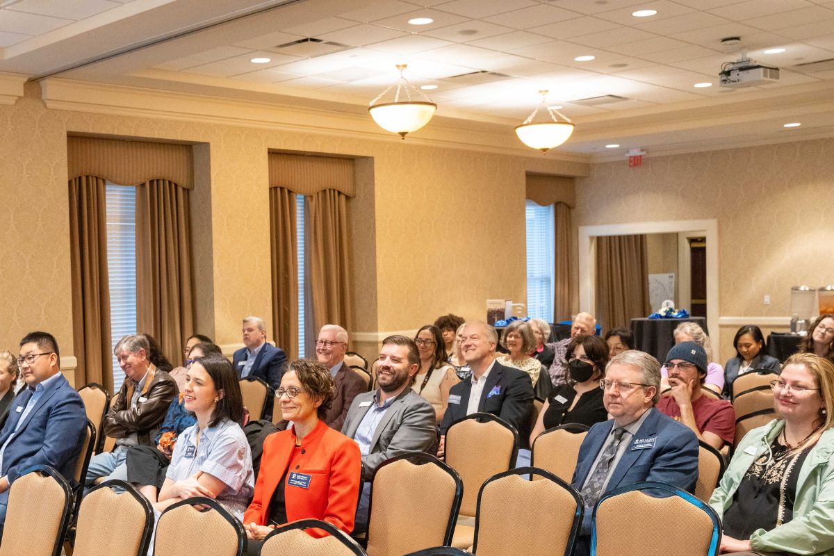Attendees sit in chairs in the audience