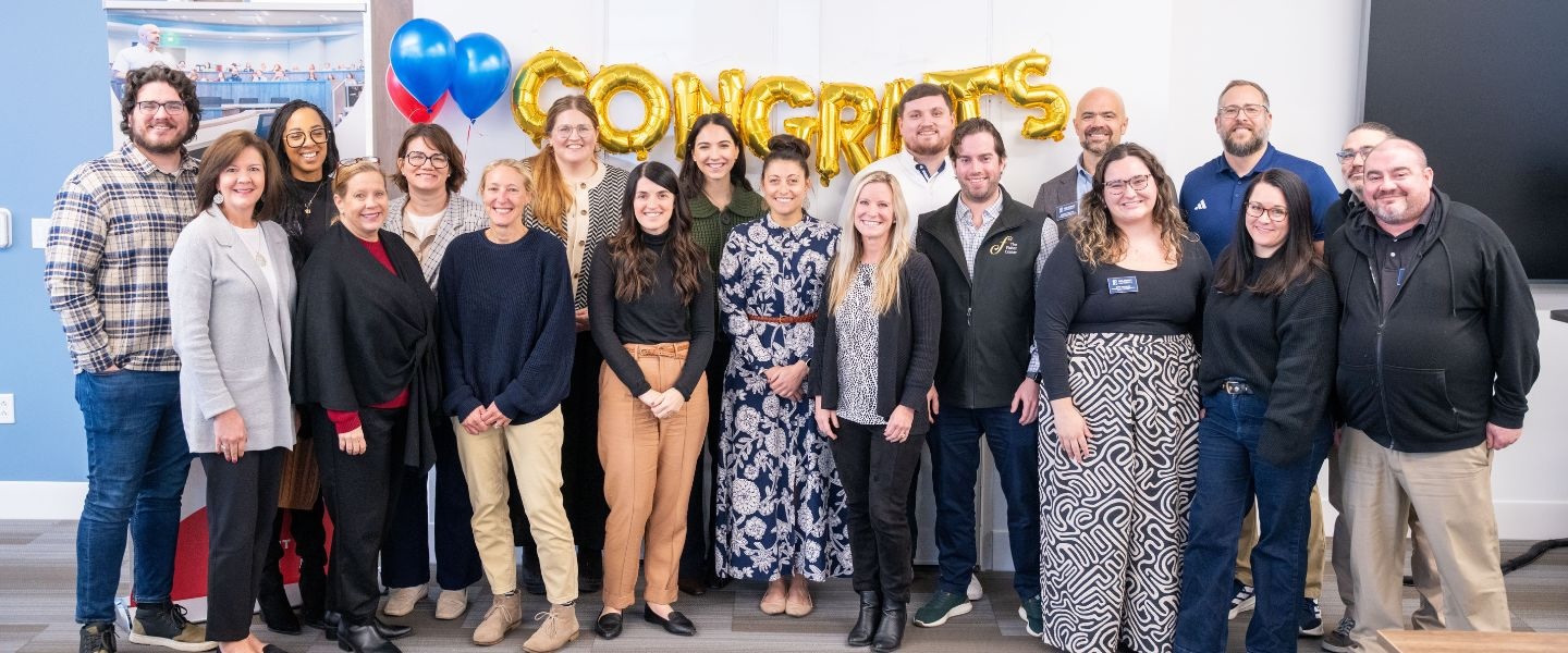 ELDP Graduates posing proudly in front of "celebrate" balloon banner