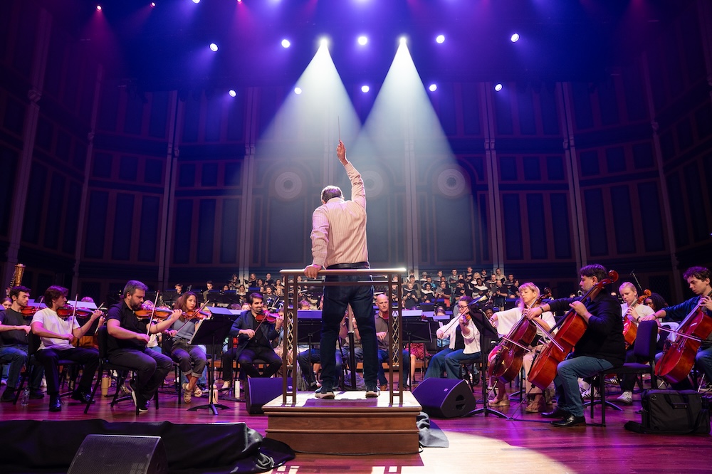 Kohen conducts orchestra at rehearsal