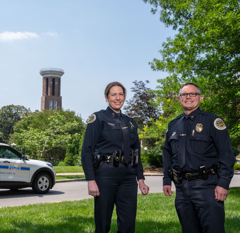 Gibson and Proctor pose in front of Bell Tower and Police Car