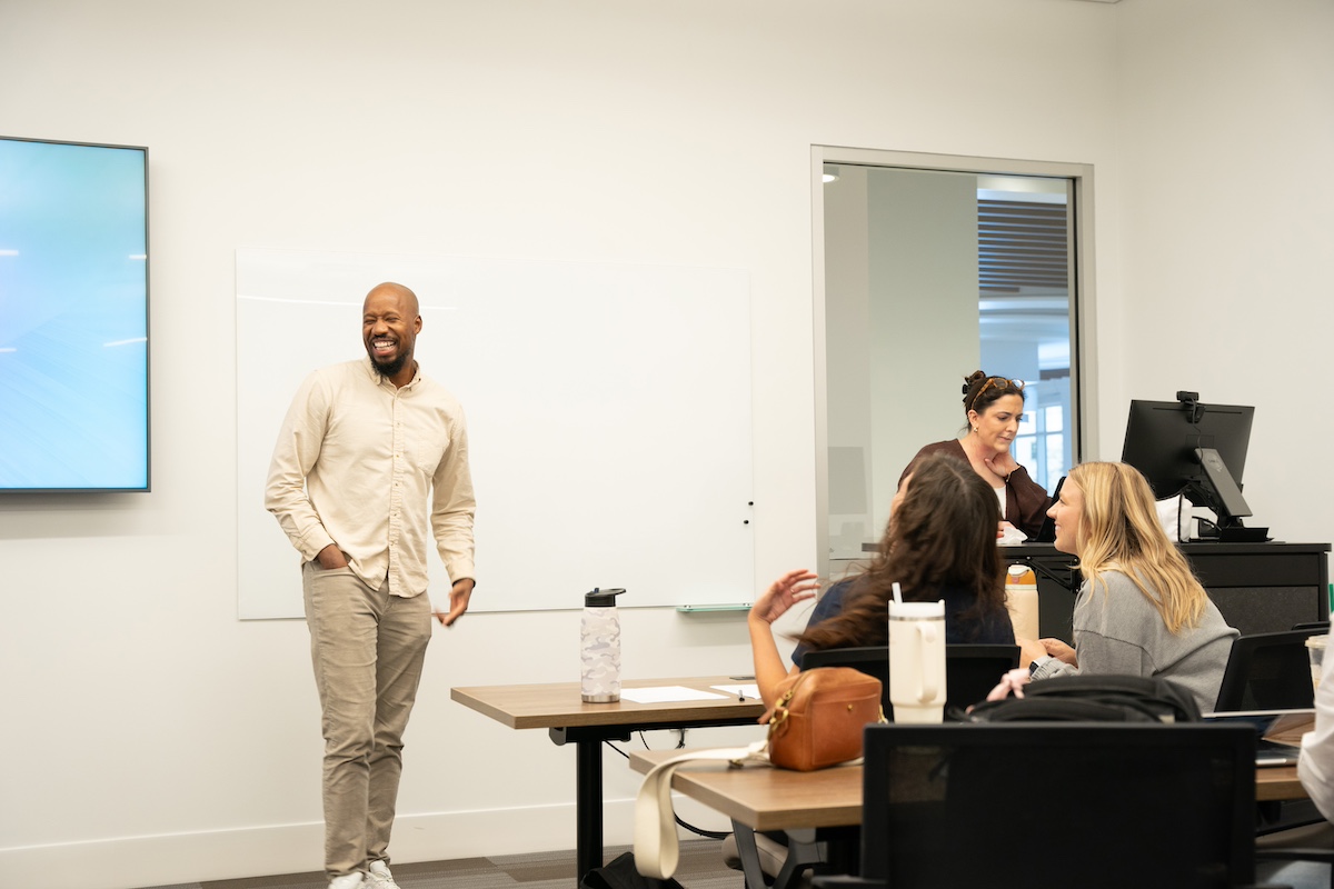 students laughing and smiling with professor in a classroom