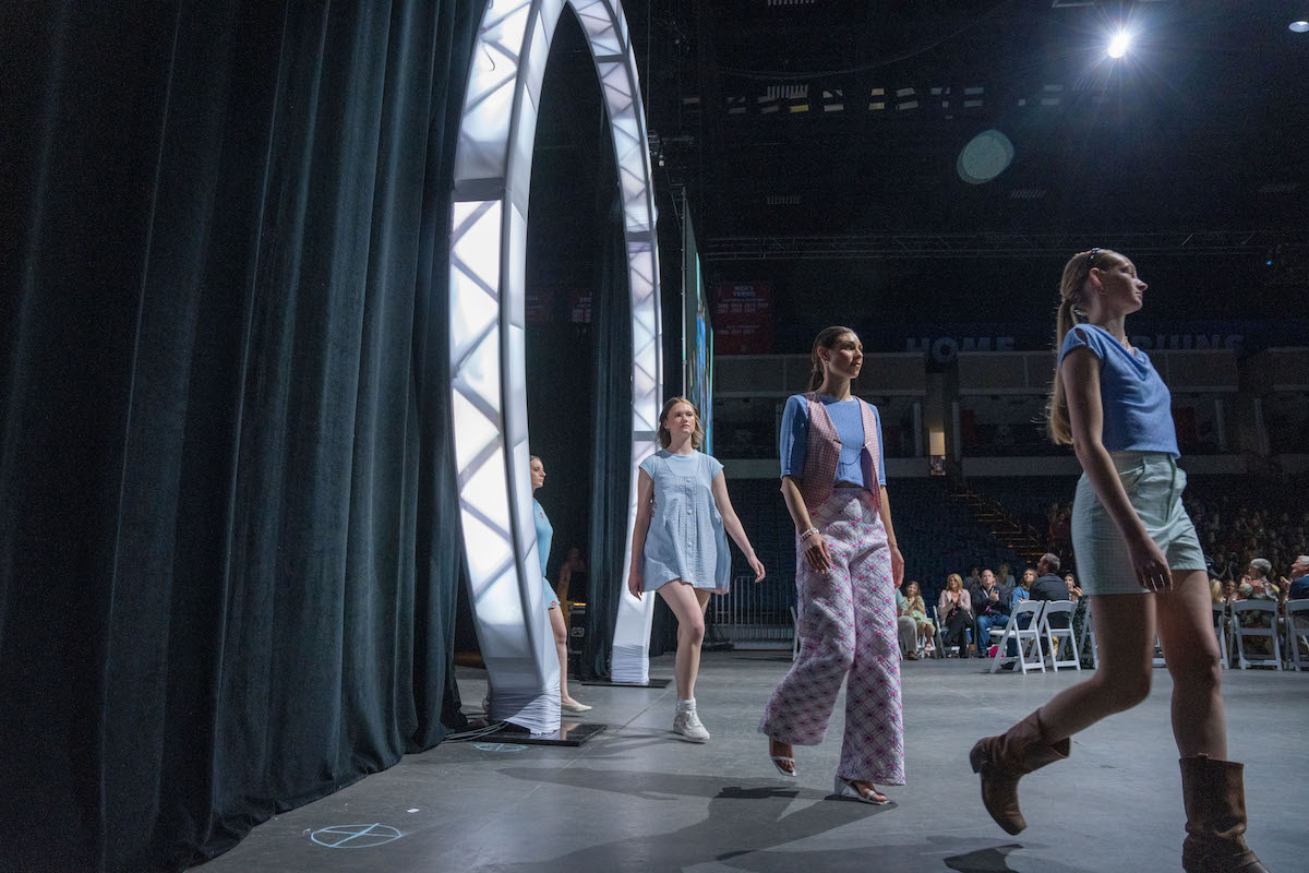 Models step onto the runway through a glowing circular arch during the 2025 O’More College Fashion Show, wearing pastel outfits designed by Jey Maroney.