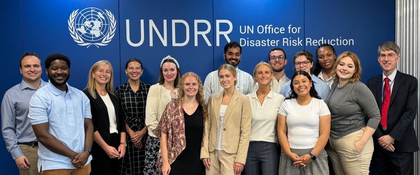 Students and faculty pose in front of the UN sign