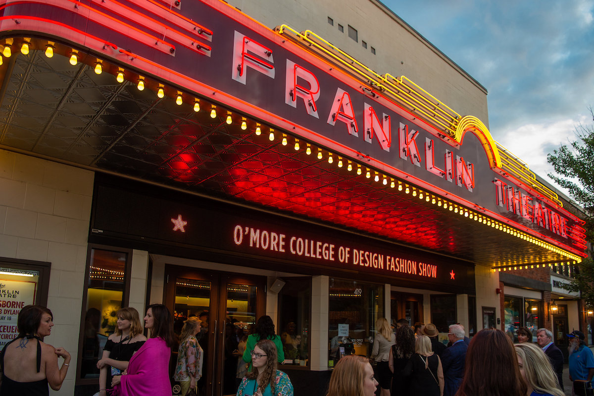 A crowd gathers beneath the glowing red Franklin Theatre marquee announcing the O’More College of Design Fashion Show in 2018.