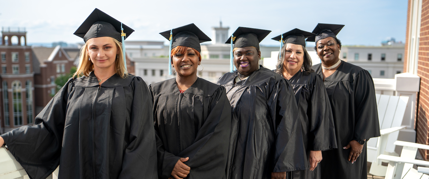 Five female graduates in a row with caps and gowns