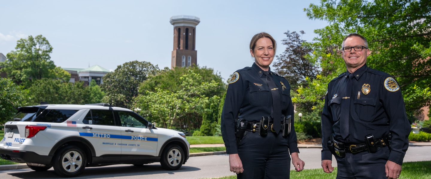 Gibson and Proctor pose in front of Bell Tower and Police Car