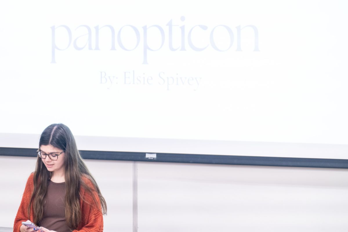 Elise Spivey reads a poem in front of a classroom