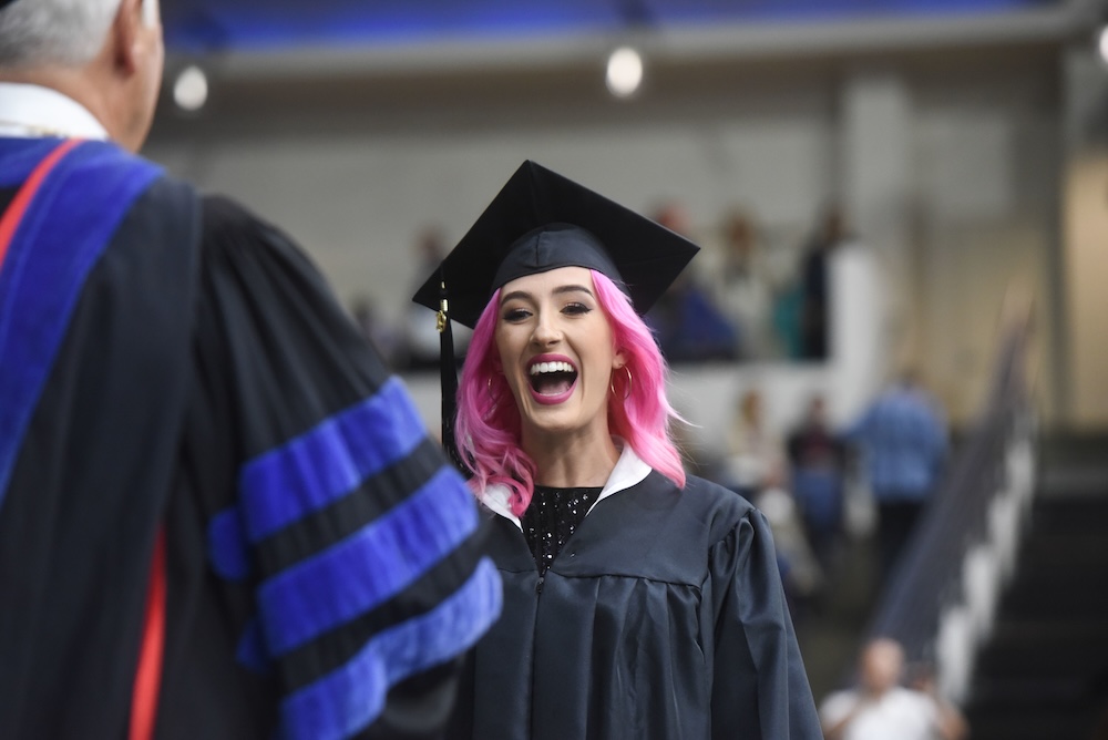 a student smiles crossing the stage at graduation