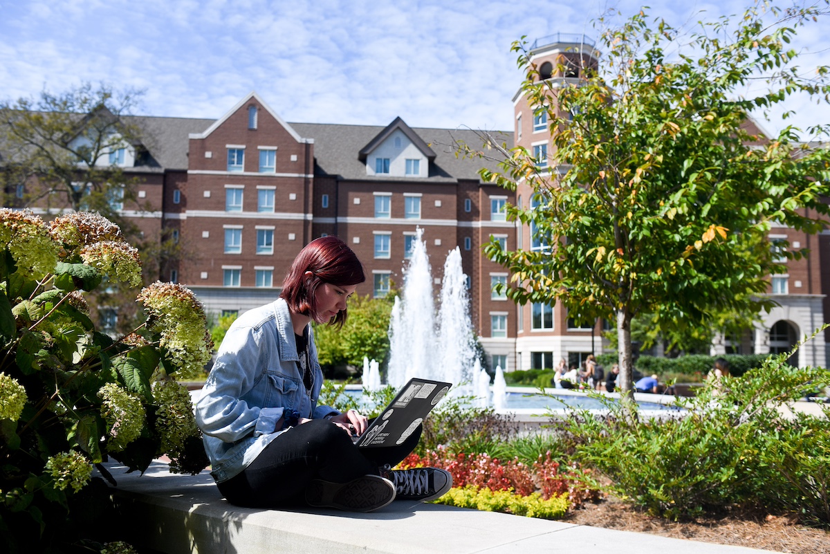 student sitting outside on a computer