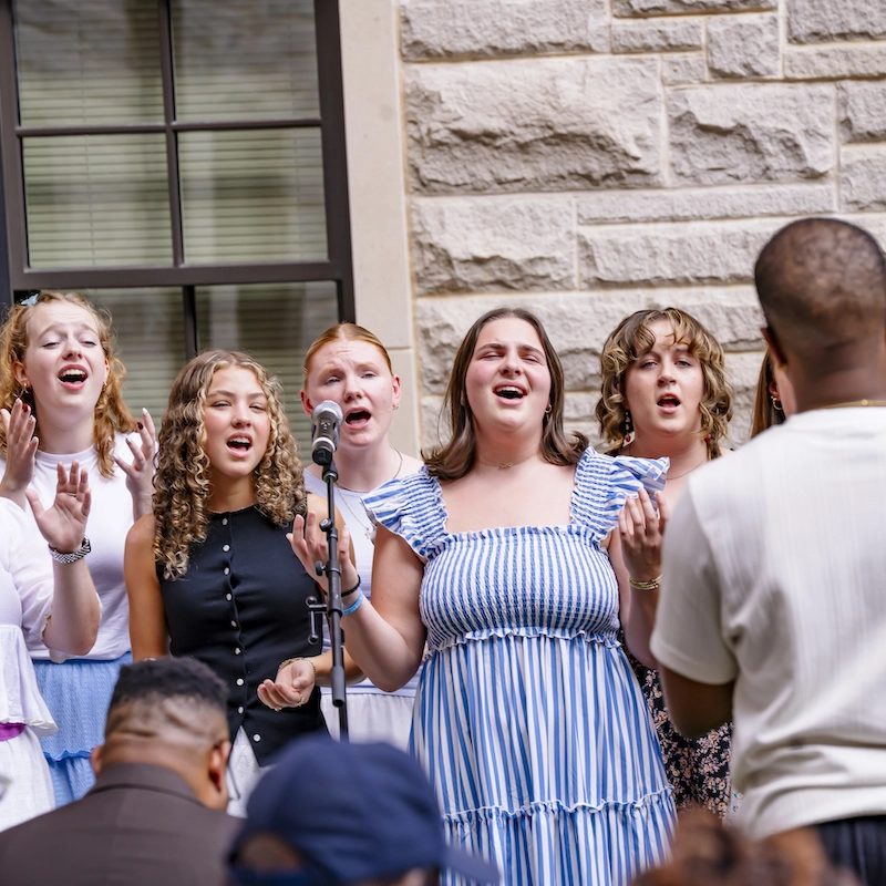 A group of students in Voxology singing at ceremony outdoors