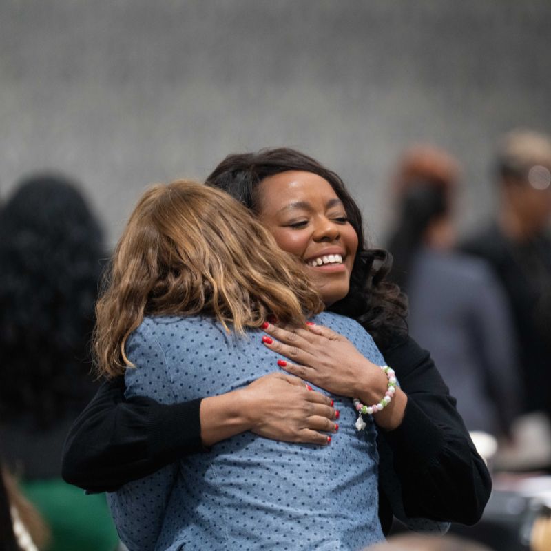 Women hug at In Her Honor luncheon