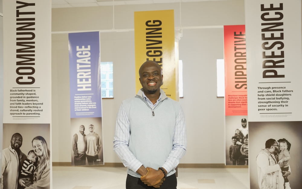 Dr. Saka posing in front of his co-created gallery exhibit "Beyond the Absent"