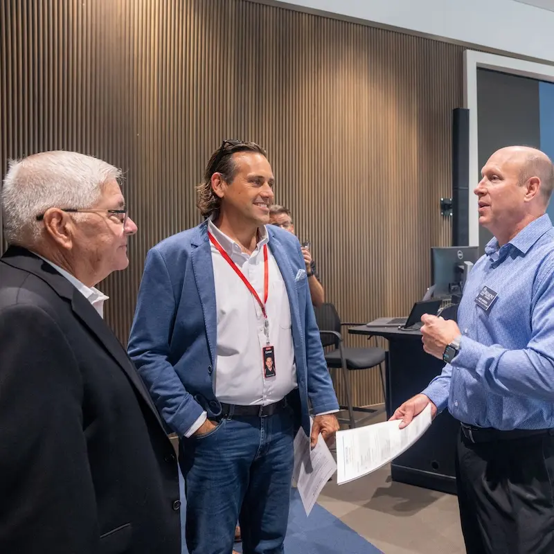 Three event attendees converse in a conference room