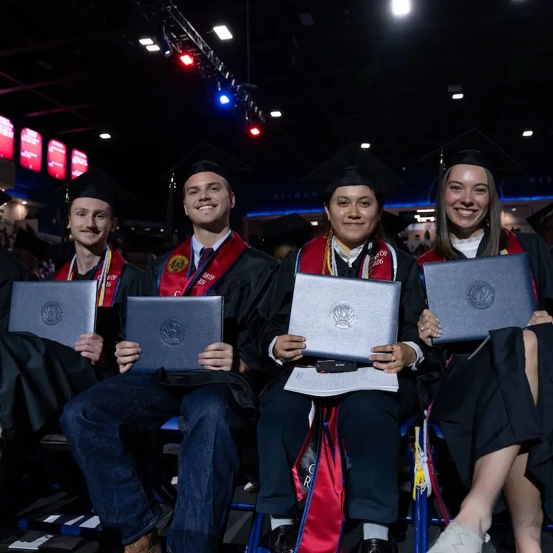 Students in graduation attire holding diplomas