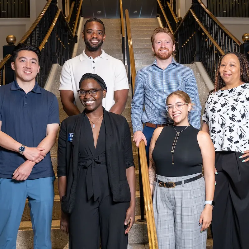 Group photo of Belmont University Faculty Fellows standing on a staircase inside a campus building.