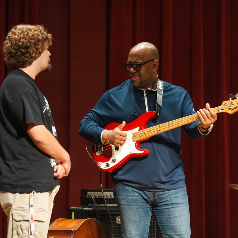 mcbride working with a student holding guitar