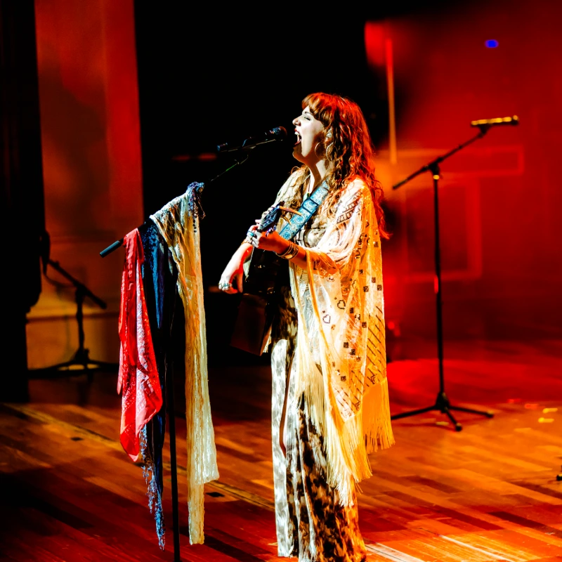 A performer singing onstage with a guitar