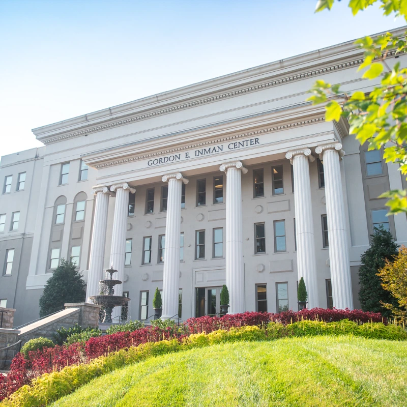 The Gordon E. Inman Center building with classical columns, a fountain and vibrant landscaping.
