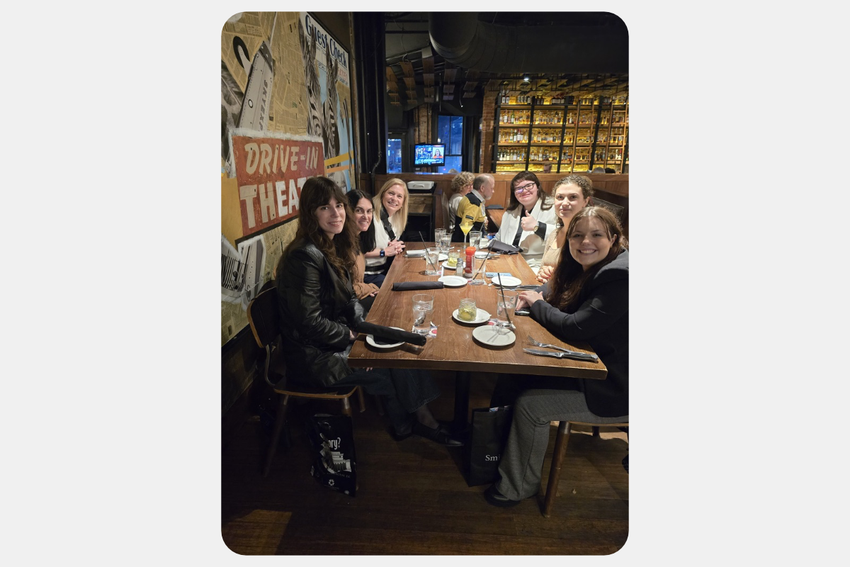 Women smiling and dining at a restaurant, with a 'Drive-In Theatre' sign and a bar in the background.