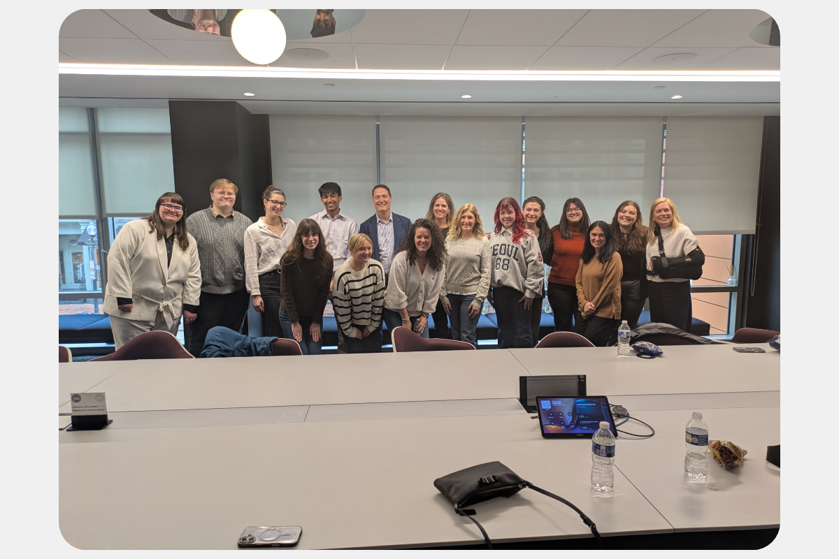 Group photo of diverse professionals and students in a modern conference room.
