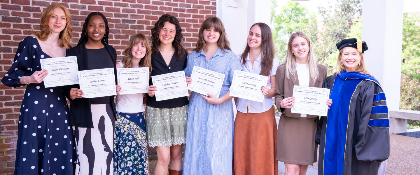 Students smiling while holding awards