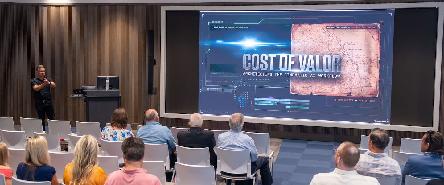 Audience watches Cost of Valor presentation displayed on a large screen