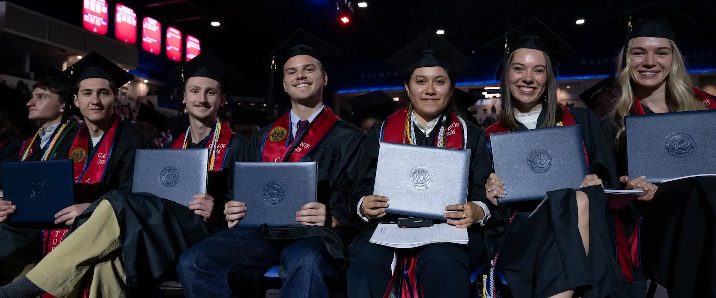 Students in graduation attire holding diplomas