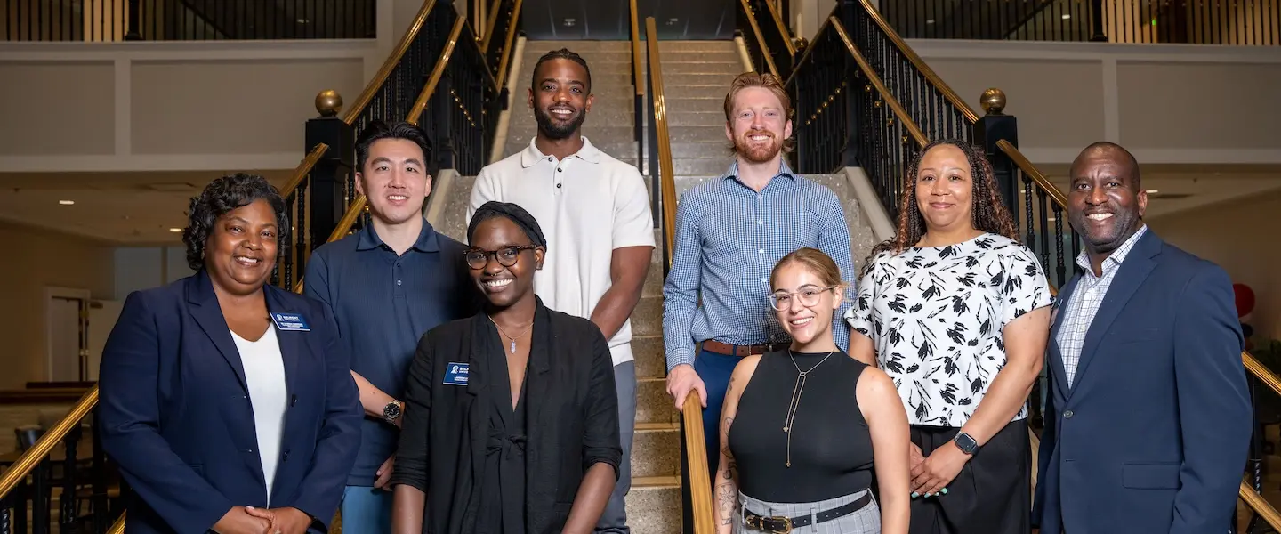 Group photo of Belmont University Faculty Fellows standing on a staircase inside a campus building.