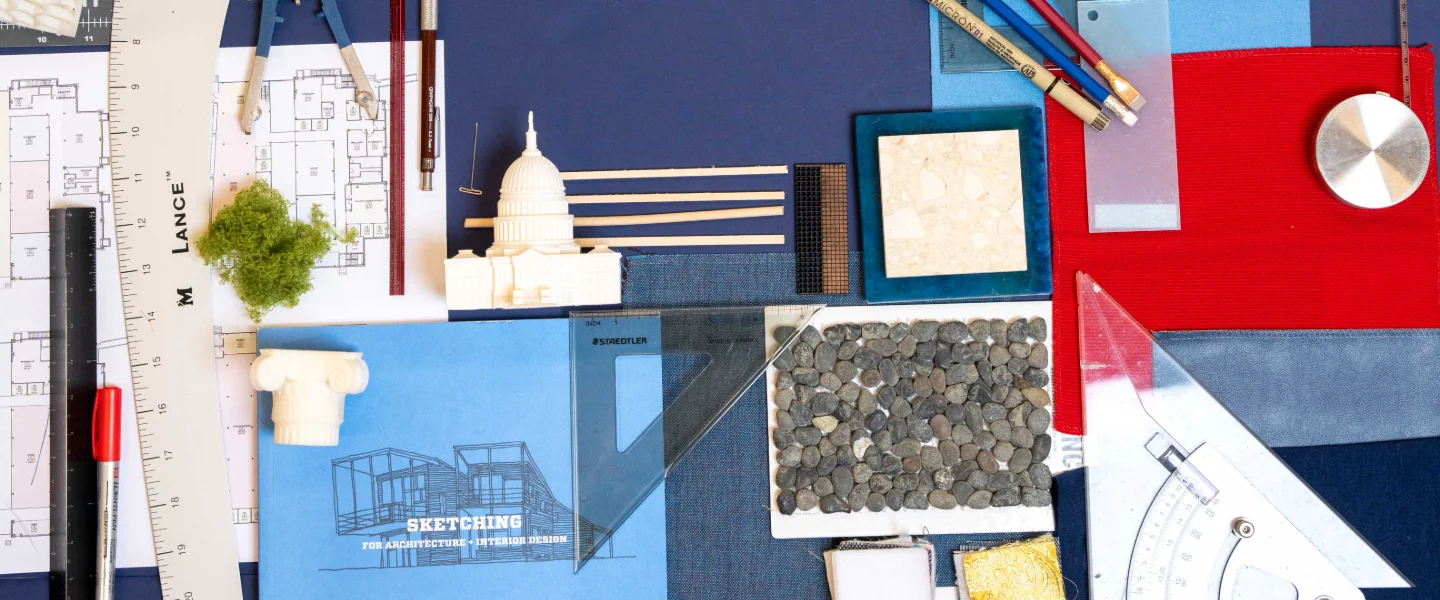 Architectural design workspace with blueprints, drafting tools, building models and material samples.