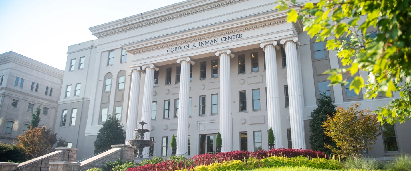 The Gordon E. Inman Center building with classical columns, a fountain and vibrant landscaping.