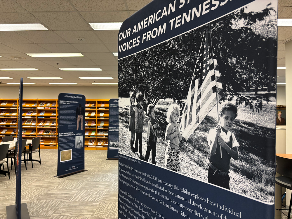 Exhibit display with historical black and white photo of children holding American flag, part of 'Our American Story' in Tennessee.