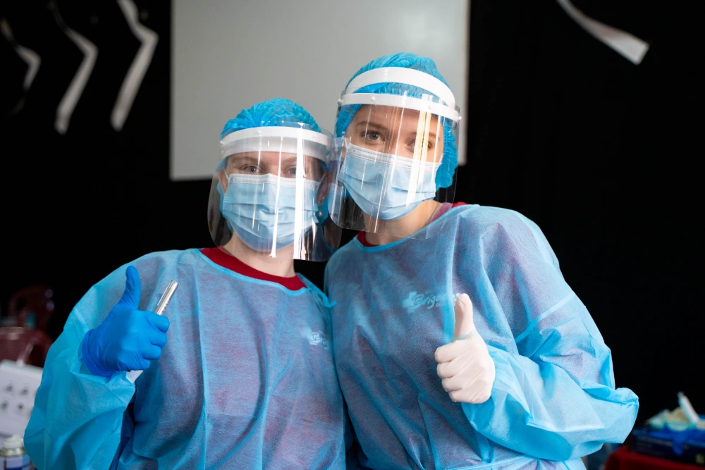 Students in gowns and masks smiling after serving in the clinic