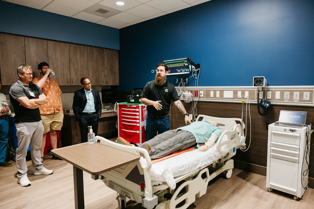 Matthew Needler, director of operations for Belmont’s Simulation Lab, demonstrates patient care technology in a hospital training room. 