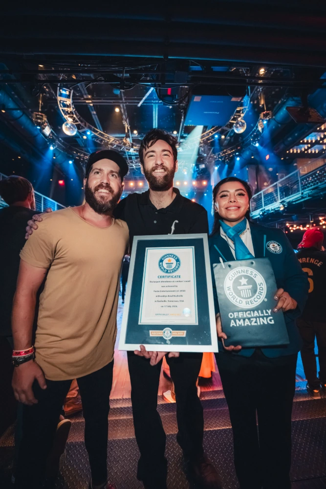 Guinness World Record recipients proudly display their framed certificate and 'Officially Amazing' bag on a stage.