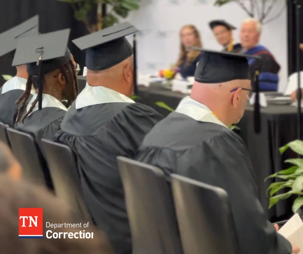 graduates sit in caps and gowns during graduation ceremony