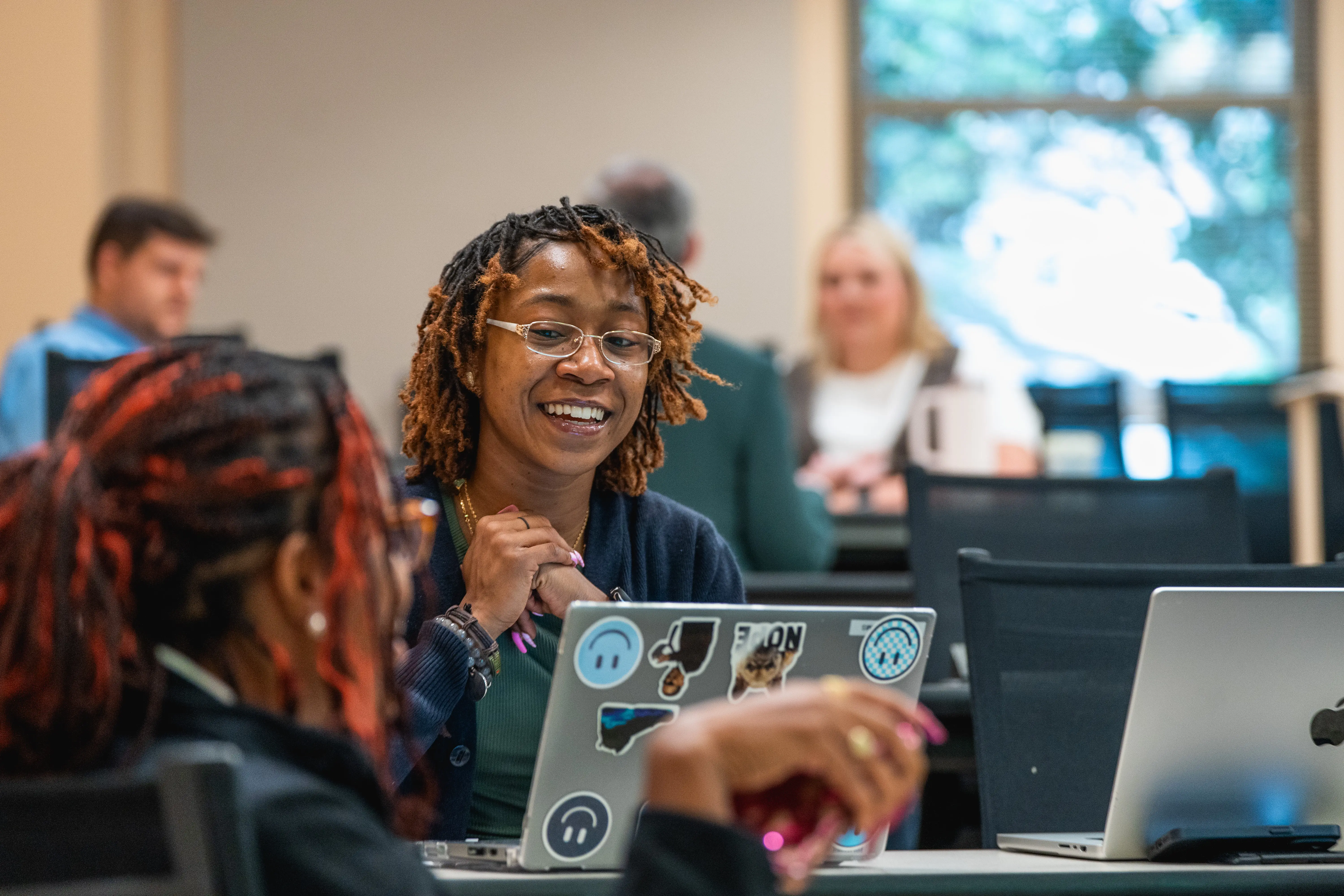 Student smiling and talking with laptop open in front of her