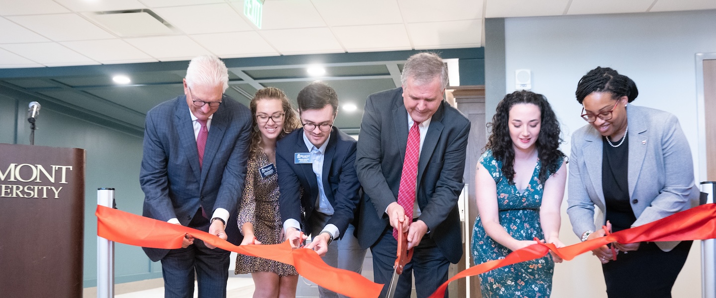 A picture of a group of people cutting a large ribbon
