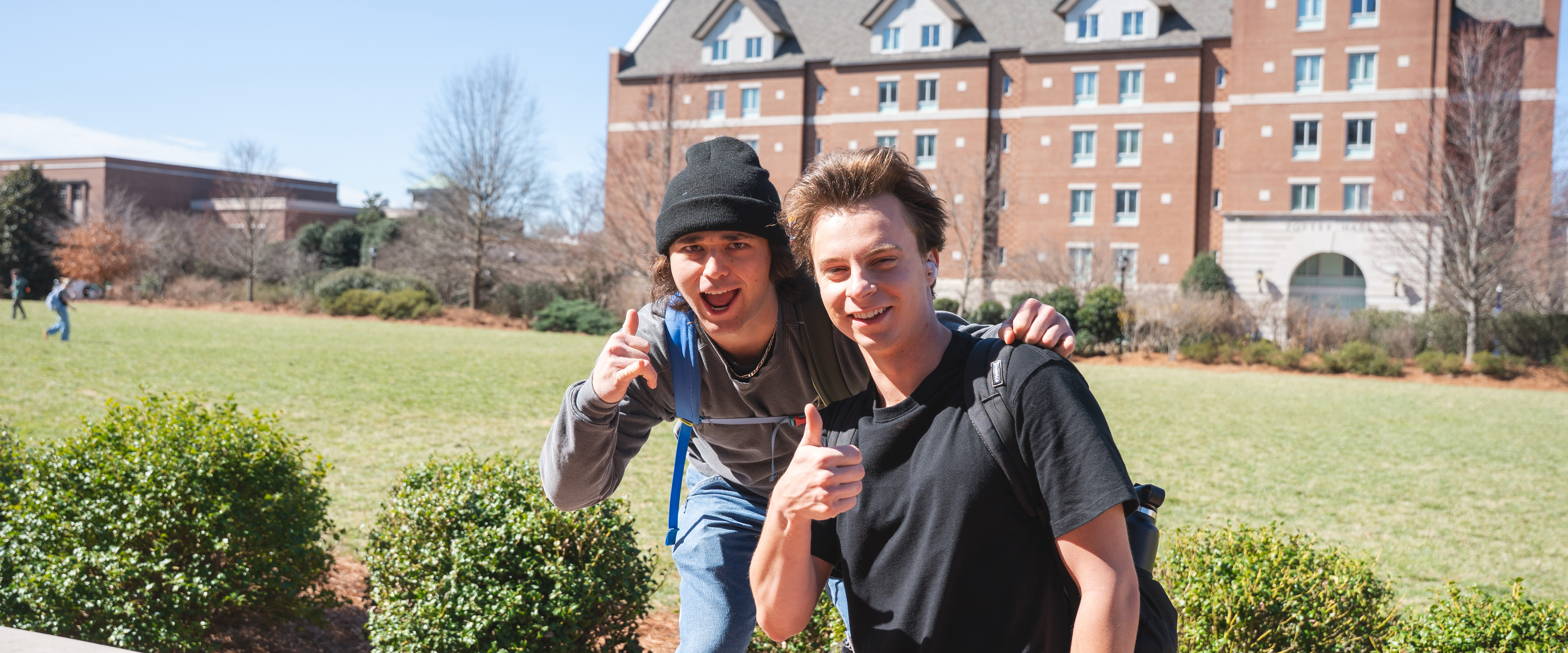 2 student smiling at the camera and giving a thumbs up