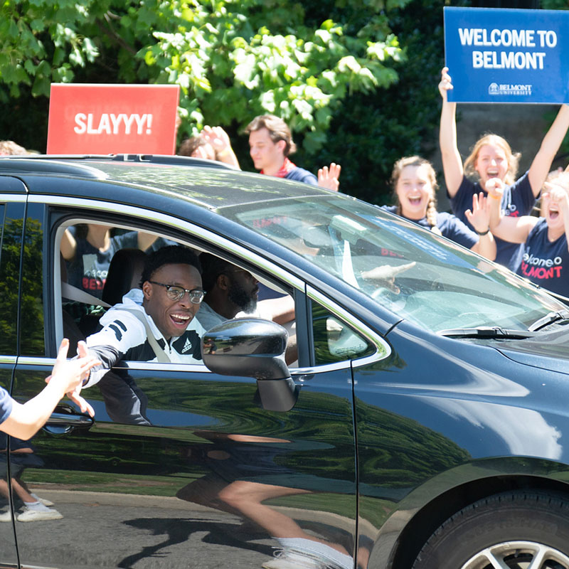 A student and his parent pulling up to their dorm on move in day to cheering students