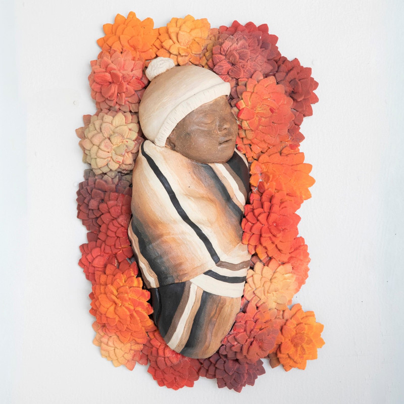 cereamic sculpture of infant among flowers
