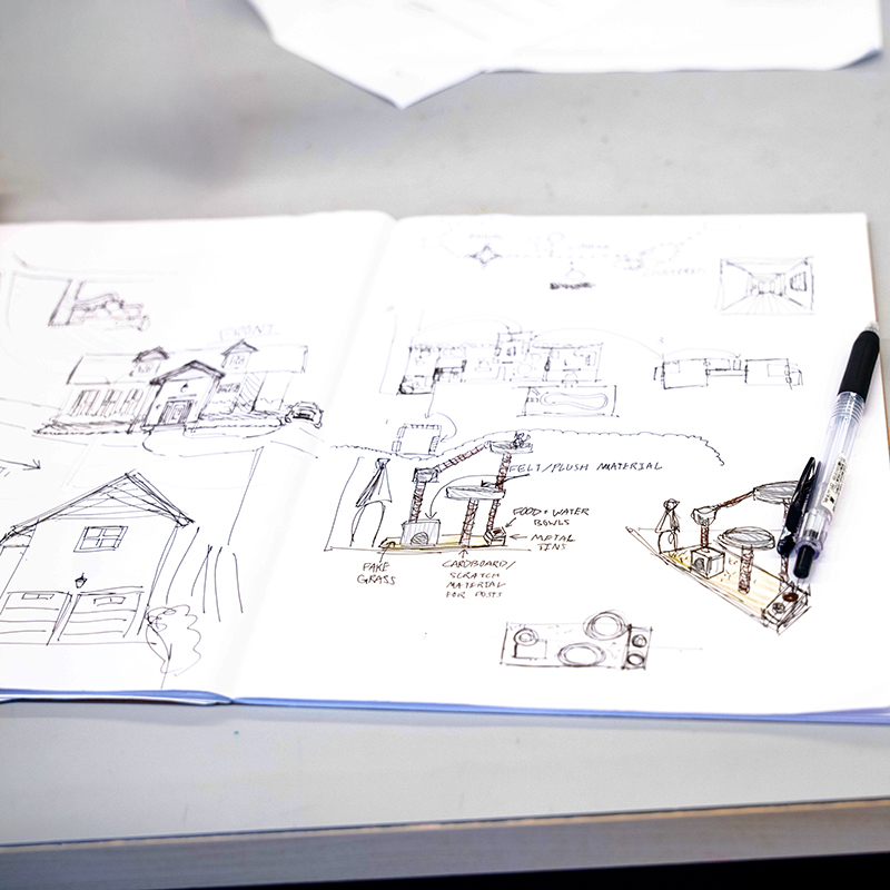 Detail shot of open sketchbook with geometric sketches of buildings and structures. 