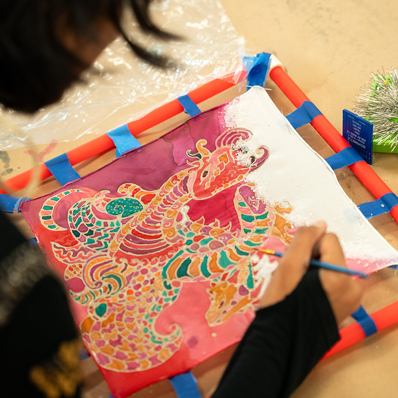 Close up of a hand painting on a stretched piece of fabric. 